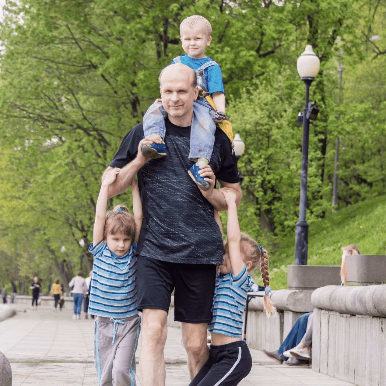Dad walking with three children hanging on him
